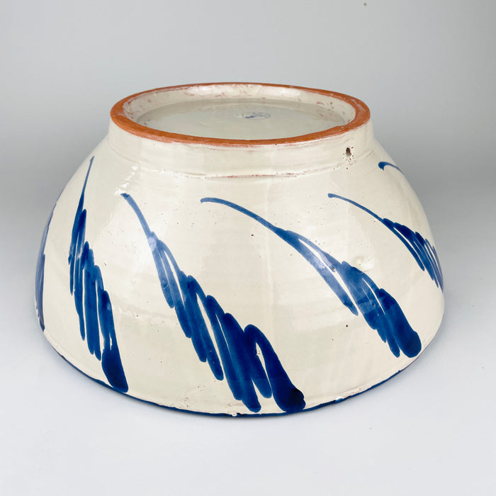 Underside of the large Spanish lebrillo bowl showing the unglazed terracotta foot ring, creamy glazed base and circular Cerámica Los Arrayanes stamp from Granada with the words Hecho a mano. The marked construction documents the bowl’s handmade Spanish origin and distinguishes it from unmarked decorative pottery in the Fajalauza tradition.