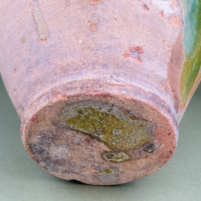 Close-up of a ceramic vase with a textured surface and green accent on a neutral background. Underside of antique French pot revealing unglazed base with kiln residue and clay texture. This view helps identify authenticity and handmade nature, suitable for collectors and designers seeking genuine antique French utility ceramics.