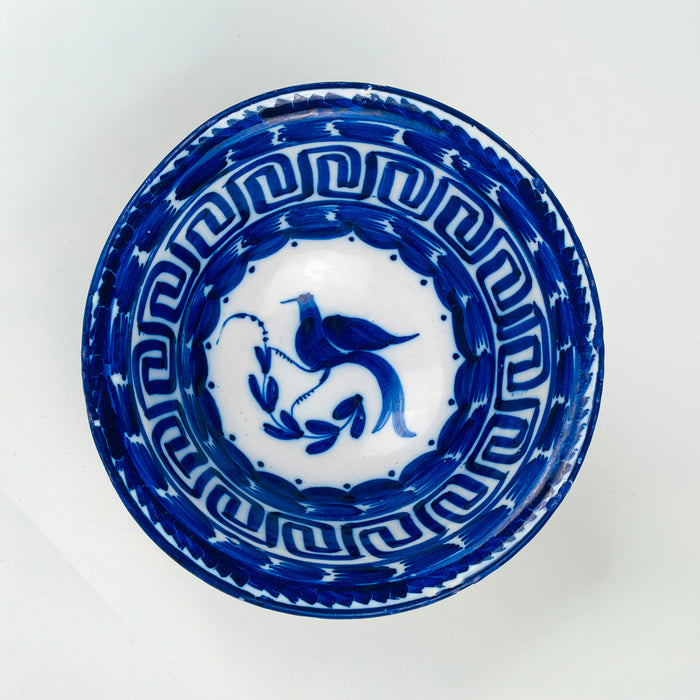 Spanish Manises blue white ceramic bowl in tin glazed earthenware, decorated with a central cobalt bird and leafy stem, framed by dotted accents and a Greek key meander border. This traditional Valencia ceramics look pairs with Mediterranean decor, French country decor, and japandi decor where one historic blue white piece adds contrast to neutral interiors.
