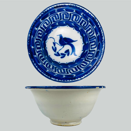Antique Spanish Manises ceramic deep bowl in blue and white tin glazed earthenware from the Valencia region, featuring a hand painted cobalt bird in the center with a curling leafy branch. The rim is structured with a Greek key border and bold cobalt brushwork, ideal for Mediterranean decor styling and blue white kitchen decor or wabi sabi decor