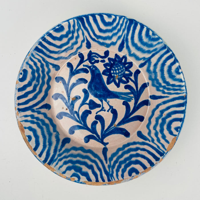 Vintage Spanish Fajalauza bowl from Granada, Andalusia, made in tin glazed earthenware and hand painted in cobalt blue. The interior shows a stylized bird among scrolling leaves with a sunflower style rosette above, framed by a wavy band rim border. Works as a decorative bowl, fruit bowl, or serving bowl for Mediterranean decor and coastal decor kitchens.
