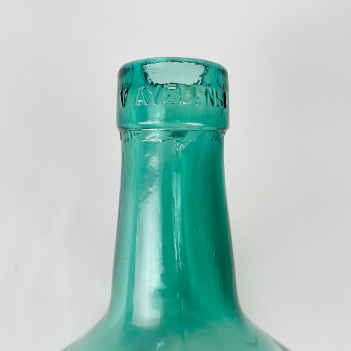 Mid 20th century Spanish glass demijohn vase in aqua blue glass, produced as a wine carboy with a large rounded body and narrow neck. The visible glass bubbles, mould seam, heavy base, and blue green color reflect utilitarian glass production while giving the piece strong appeal as a decorative floor bottle or large glass vase.