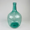 Large blue glass carboy with Spanish demijohn form, rounded storage bottle body, and narrow neck with embossed maker lettering. Originally intended for wine or liquid storage, this vintage glass vessel now works as a decorative vase for tall stems, dried flowers, branches, or empty display in Mediterranean decor and rustic home decor.