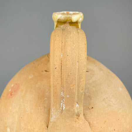 Side angle of the antique French water jug, showing its soft tapered shape and warm unglazed clay surface. The yellow-glazed neck and handle junction are classic details of early 1900s French pottery, ideal for collectors of Mediterranean farmhouse ceramics or vintage terracotta.