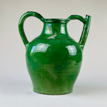 Side profile showcasing the elongated neck, pinched spout, and rear stabilizing handle of the green-glazed gargolette
A side-angle detail view of the vintage French pottery gargolette reveals the tall narrow neck, pinched pouring spout, and back handle designed for grip. The lead-based green glaze and hand-shaped form evoke traditional rural ceramics from 19th-century Southwest France.
