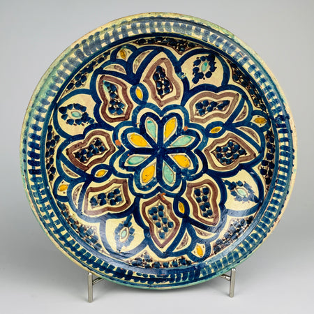 Full view of a vintage Moroccan ceramic bowl hand-painted in cobalt blue, ochre, turquoise, and plum, featuring a mandala-style floral pattern and footed base. This Fez pottery bowl reflects traditional Moroccan craftsmanship ideal for Mediterranean or bohemian interiors.