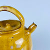 Antique yellow terracotta water jug from France, with a rounded body, upper honey glaze, narrow spout, pierced lid, and carrying handles. This gargoulette pot was made as utilitarian pottery and now reads as a decorative ceramic vessel, suitable for rustic home decor, Mediterranean decor, farmhouse decor, or a collected French pottery display.