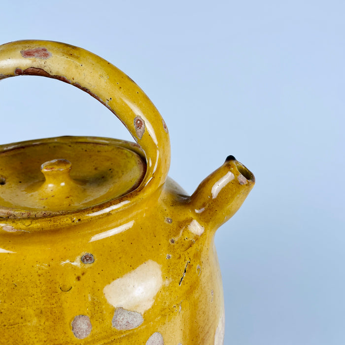 Antique yellow terracotta water jug from France, with a rounded body, upper honey glaze, narrow spout, pierced lid, and carrying handles. This gargoulette pot was made as utilitarian pottery and now reads as a decorative ceramic vessel, suitable for rustic home decor, Mediterranean decor, farmhouse decor, or a collected French pottery display.