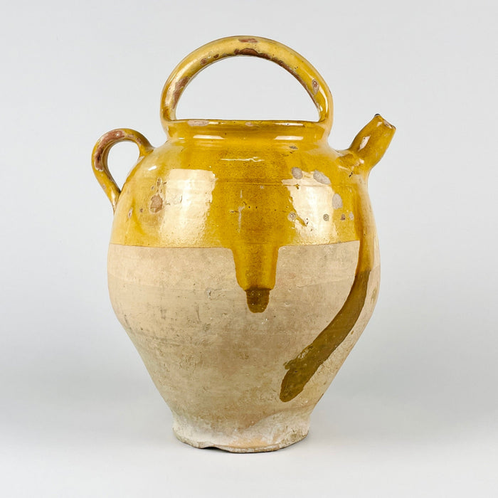 Large antique French yellow gargoulette pot in glazed terracotta, made as a 19th century water jug with an arched carrying handle, side spout, side loop handle, and removable lid. The upper section has honey yellow glaze, while the lower body shows pale unglazed terracotta with patina, making it suitable for French country decor and rustic home decor.