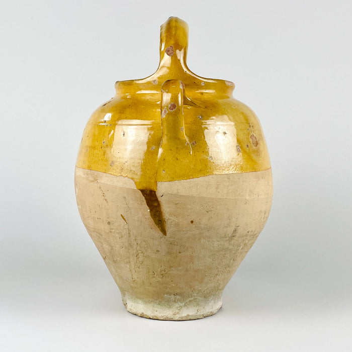 Rustic French pottery vase in the form of an antique terracotta gargoulette water jug, finished with yellow glaze across the top and raw beige clay across the lower body. The removable lid, side spout, and two handles show its original water vessel function, while the worn surface makes it suitable for French country and farmhouse decor.