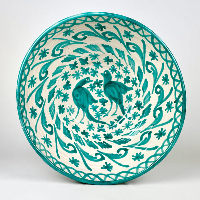 Large Spanish Fajalauza lebrillo bowl in hand painted green terracotta, with a cream white glazed ground, twin bird motif, scrolling foliage, floral decoration, and a green rim. The deep rounded form and pierced reverse hole make it suitable as a decorative bowl, ceramic wall hanging, or Mediterranean decor object.
