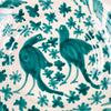 Spanish ceramic wall art made from a Fajalauza lebrillo bowl, with hand painted green birds, floral motifs, leafy vines, and a repeating border around the rim. The bowl is glazed over terracotta and designed for display as a wall hanging, table centerpiece, or decorative ceramic object in Spanish pottery decor.