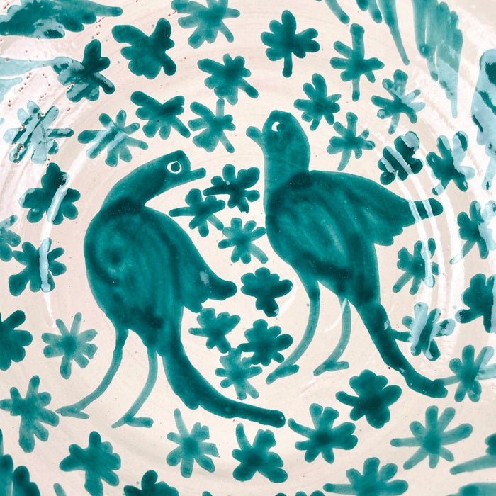 Spanish ceramic wall art made from a Fajalauza lebrillo bowl, with hand painted green birds, floral motifs, leafy vines, and a repeating border around the rim. The bowl is glazed over terracotta and designed for display as a wall hanging, table centerpiece, or decorative ceramic object in Spanish pottery decor.