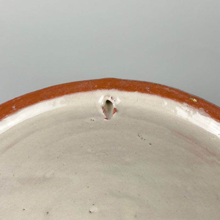 Mediterranean decor object in Spanish Fajalauza pottery, formed as a large lebrillo bowl with green bird decoration and a cream glazed terracotta body. The scrolling foliage, small flowers, border pattern, and pierced hanging hole make it a strong ceramic wall hanging for kitchens, dining rooms, or collected pottery displays.
