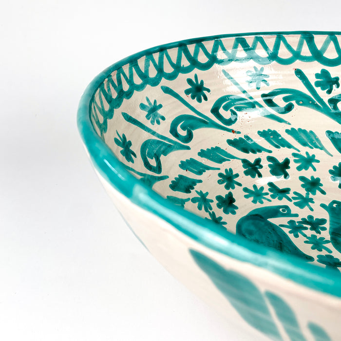 Large Spanish ceramic bowl in Fajalauza style, with green hand painted birds, small flowers, leafy scrolls, and a cream white glazed interior. The terracotta body, rounded lebrillo shape, green rim, and reverse hanging hole make it a decorative wall bowl for Spanish pottery collectors and Mediterranean interiors.