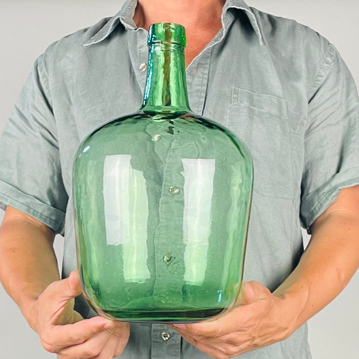 vintage green glass demijohn by Spanish maker VIRESA, produced in Benigànim, Valencia, circa 1960s. This mould blown 5 L wine carboy combines a softly rounded body, sloping shoulders and long narrow neck with transparent aqua green glass, scattered seed bubbles and darker emerald color through the thick base, ideal as a decorative bottle vase.