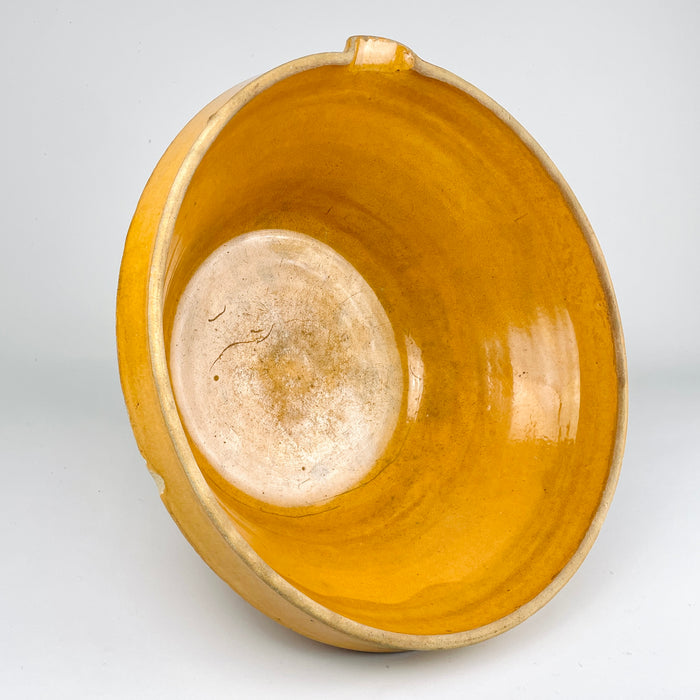 A detailed view of the interior of this warm amber ochre glazed terracotta bowl reveals the rich colour, glossy surface and characteristic glaze shading associated with antique French culinary pottery. The thick terracotta walls and gentle curves show the functional design of a traditional jatte or terrine used in rural kitchens. This piece complements rustic kitchen decor, country cottage decor, and farmhouse decor.