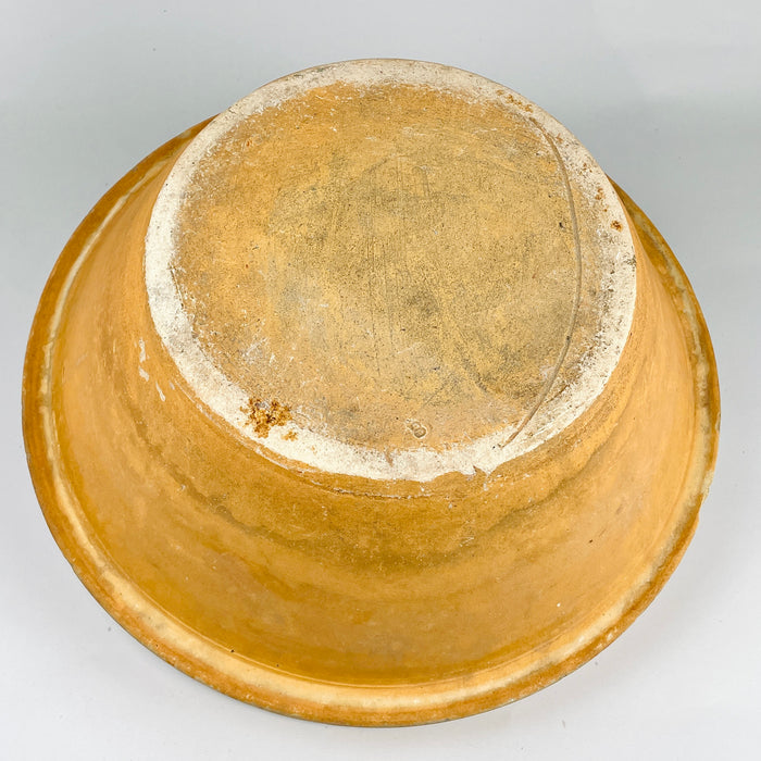 Underside photograph showing the raw terracotta base, firing ring, and wear marks typical of 19th century French terracotta. The unglazed foot and textured clay surface reinforce the authenticity of this warm amber ochre glazed bowl, making it suitable for collectors of French country ceramics and rustic pottery.