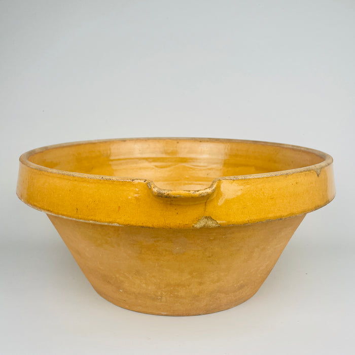 Top view photograph capturing the full interior surface of the warm amber ochre glazed bowl, showing firing variation and glaze movement. This antique French terracotta bowl is suitable for display on shelves, tables or kitchen counters within rustic home decor or French country settings.