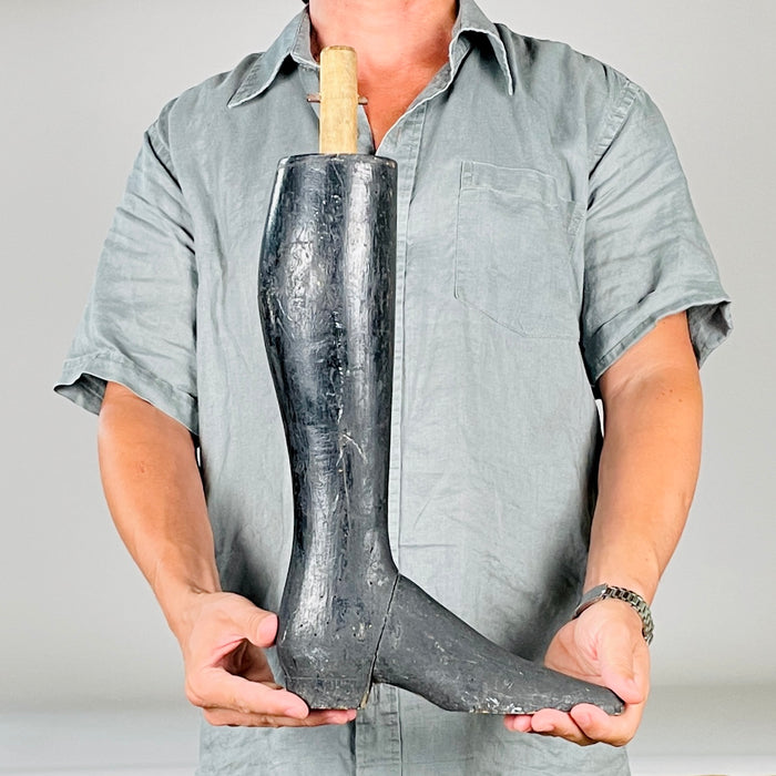 Heavy solid wood French tailor’s mannequin leg with pronounced wear along the sole, toe and block heel. Exposed pale timber contrasts with the black painted calf and boot, while the long narrow shape preserves the stylized proportions of a nineteenth century display figure. It makes an arresting sculptural object for maximalist decor.