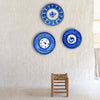 Hand painted Spanish majolica plate from Manises with deep cobalt blue decoration over a warm white glaze. The signed charger combines dense geometric repetition around the rim with looser botanical symbols at the center, producing a graphic handmade surface. Small chips and glaze losses around the edge are visible and consistent with age.